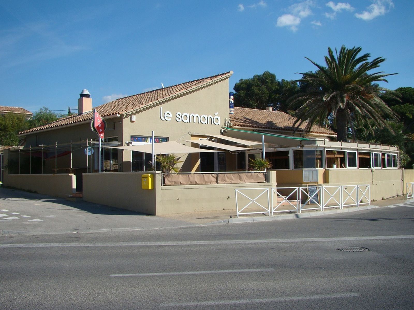 La façade du restaurant, toit de tuiles, palmier et enseigne « le samaná » en lettres blanches